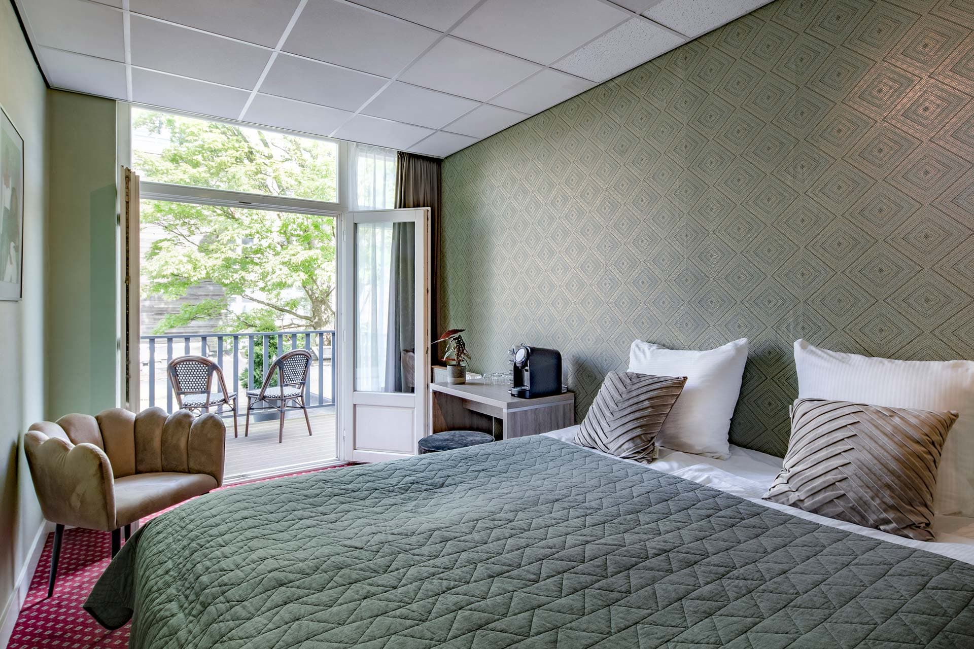 A double room with the balcony doors open onto the trees