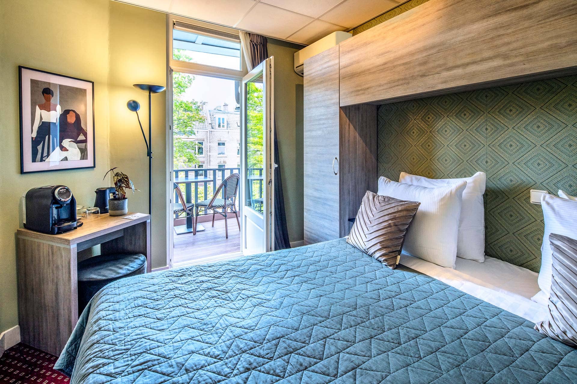 A double room with its desk, coffee machine and balcony beyond